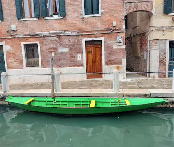 narrow green boat in venice